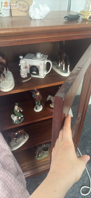 Oak glass cabinet that has a brass handle.