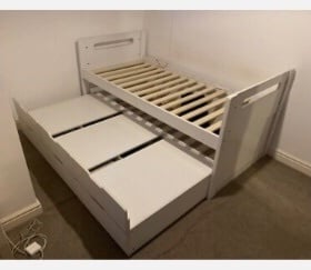 White wooden single bed with a pull-out trundle bed underneath