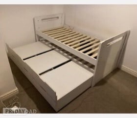 White wooden single bed with a pull-out trundle bed underneath in Reigate