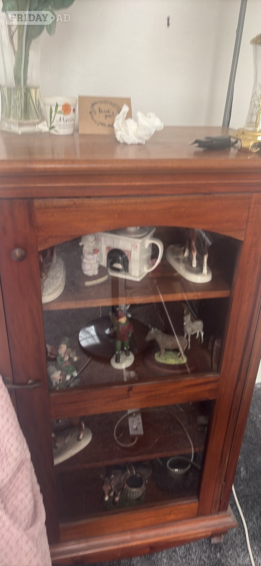 Oak glass cabinet that has a brass handle.